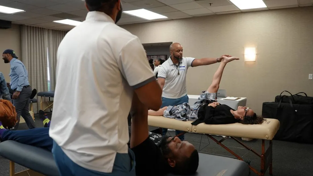 Ben demonstrating an assisted stretch to a room of students