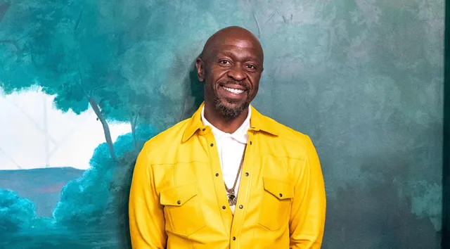 Benjamin Atanga, founder of The Stretch Loft, smiling in a yellow shirt